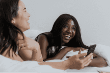 An image of two women sat at a breakfast table looking at a phone